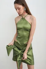 Falda corta verde oliva confeccionada en tafeta, con diseño cruzado y un gran moño anudado en el frente.