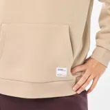 Buzo de chándal con capucha color beige, con cordones ajustables, bolsillo canguro frontal y puños y dobladillo acanalados.