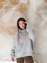 Sweater de lana gris con diseño de líneas y formas geométricas en color rosa.