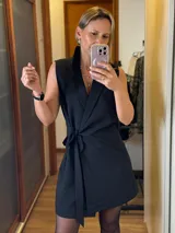 Chaleco vestido color rosado, de corte recto, sin mangas, con cuello tipo blazer y lazo para atar en la cintura.