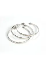 Set de tres brazaletes plateados con textura y terminaciones redondeadas.