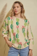 Buzo tejido de punto con diseño estampado de cactus en tonos verdes y rojos sobre base color crema. Presenta cuello redondo y mangas largas con puños acanalados.