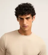 Buzo de algodón y poliéster color beige, con cuello redondo, mangas largas y puños ajustados. Diseño liso y minimalista.