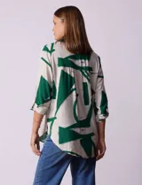 Camisa de manga larga con estampado abstracto en tonos verde y blanco. Cuello con solapa y abertura central con botones. Largo de manga regulable con presilla y botón. Terminación de ruedo anudada opcional.