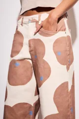 Pantalón jean de corte wide leg con estampado de manchas marrones y detalles de estrellas azules.