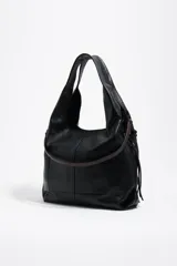 Bolso grande de cuero negro tipo shopper, modelo Paper de Bimba y Lola, con doble asa de hombro, detalles de cordones trenzados decorativos y el logo impreso en plateado en la parte inferior.