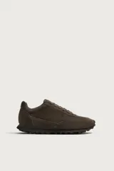 Zapatilla deportiva de hombre confeccionada en piel con acabado de serraje, diseño de paneles y suela dentada.