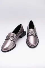 Mocasines de cuero metalizado en tono peltre, con detalle de herraje metálico en el empeine y taco cuadrado bajo.