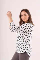 Pijama de dos piezas, compuesto por una remera de manga larga blanca con lunares negros y un pantalón largo gris.