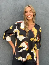 Blusa de satén con escote en V y mangas tres cuartos acampanadas, con estampado abstracto en tonos negro, caramelo, verde lima y blanco.