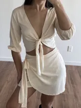 Minifalda tipo wrap de color crudo, con diseño cruzado y lazo lateral ajustable. Confeccionada en tela slab.