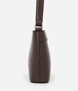 Bolsa bandolera de estructura firme en color marrón oscuro, con cierre de cremallera metálica y correa larga ajustable con hebilla.