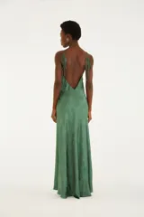 Vestido largo verde con estampado sutil de conchas marinas, escote halter y tirantes finos. Presenta un diseño fluido y silueta recta con escote en la espalda.