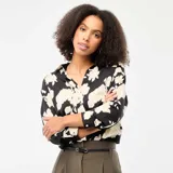 Blusa de corte fluido con estampado floral en contraste, cuello camisero, cierre frontal de botones y mangas tres cuartos.