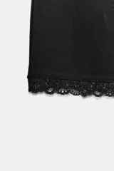 Minifalda negra de tiro medio y cintura elástica, con detalle de encaje a tono en el borde inferior.