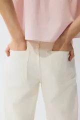 Pantalón jean de tiro alto en color crudo, con diseño de cinco bolsillos, corte recto y holgado de cadera a bajo.