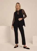 Pantalón negro de crepe con diseño entallado, cinturilla con trabillas y hebilla ajustable, cintura alta, cierre de cremallera frontal y cuatro bolsillos.