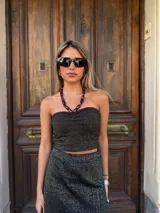 Falda corta tejida color gris con detalles dorados, con flecos largos en el ruedo.