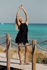 Vestido mini negro de cuello halter y espalda descubierta, con diseño de múltiples volantes en cascada.