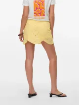 Short pollera color amarillo pálido con bordado de puntilla, corte mini y cierre lateral oculto.