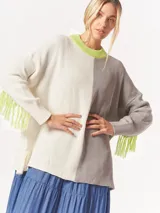 Buzo tejido oversized con bloques de color blanco y gris, cuello redondo en verde neón, tajos laterales y flecos verdes en las mangas.