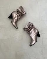 Botines dorados de cuero vacuno con punta fina y tacón aguja.