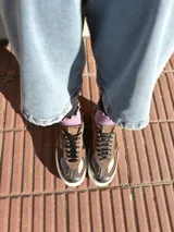 Zapatillas deportivas de cuero color peltre, con cordones negros y suela de goma blanca.