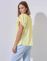 Blusa amarilla con textura labrada, escote redondo elastizado y mangas cortas con aberturas y lazos.