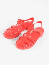 Sandalia tipo cangrejera de PVC color rojo, con diseño de tiras entrelazadas y cierre de hebilla en el tobillo.