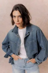 Camisa de denim de lavado medio con calce oversize, cuello camisero, cierre frontal con botones y bolsillos aplicados en el frente.