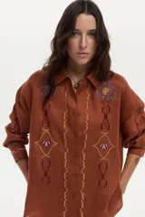 Camisa de lino color ladrillo, con mangas largas y bordados decorativos en el pecho y las mangas.