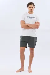 Short de baño cargo color negro, de diseño liso con bolsillos laterales y bolsillos utilitarios con solapa y botón en las piernas. Cuenta con cintura elástica ajustable mediante cordón.