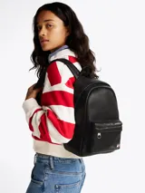 Mochila negra de poliuretano con acabado liso y diseño curvo. Tiene un compartimento principal con cierre de cremallera oculta, asa superior, correas ajustables y acolchadas, bolsillo interior de malla y bolsillo exterior con cremallera. Incluye inscripción de Tommy Jeans en las tiras e insignia de Tommy en la parte delantera.