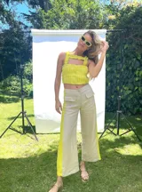 Pantalón de lino color beige con franja vertical amarilla en los laterales, tiro medio y corte palazzo.