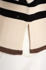 Sweater de punto a rayas horizontales negras y crudas, con cuello redondo y mangas largas. Tiene ribete marrón en puños y ruedo.