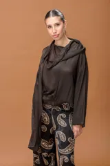 Blusa de tela satinada color marrón oscuro, con cuello drapeado y mangas largas con puños elásticos. Presenta un diseño holgado con ruedo ajustado.