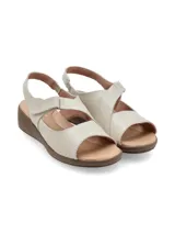 Sandalias de cuero color crudo con plataforma baja y suela marrón. Cuenta con tira ajustable con velcro en el empeine y diseño destalonado.