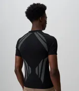 Remera masculina de poliéster seamless con corte ajustado, cuello redondo y manga corta. Presenta un diseño negro con perforaciones estratégicas y tramas geométricas en contraste en los hombros, laterales y frente.