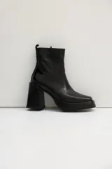 Botas negras de cuero sintético, con caña corta, plataforma y taco cuadrado. Cierre lateral con cremallera.