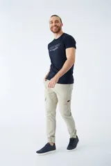 Pantalón cargo color verde oliva, de corte slim, con cintura elastizada y cordón ajustable. Presenta bolsillos laterales tipo cargo con botones y puños elásticos en los tobillos.