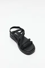 Sandalias color marrón con tiras trenzadas y ajuste de velcro en el talón. Plataforma de 3cm de alto y suela negra.