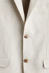 Blazer de lino slim fit color beige, con solapas de muesca, cierre de un botón central, bolsillos con solapa en el frente y bolsillo ojal en el pecho.