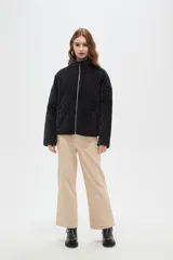 Campera de estilo bomber con diseño capitoneado en forma de rombos, color negro con efecto lavado. Presenta cuello alto, cierre frontal metálico y bolsillos laterales.