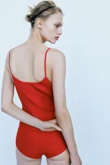 Body confeccionado en mezcla de viscosa y poliamida, color rojo. Presenta un diseño de punto rib con escote en pico, tirantes finos y cierre inferior con botones a presión.