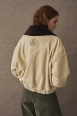 Campera bomber de paño color azul marino, con cuello de piel sintética en color marrón desmontable, cierre frontal y puños elásticos. Presenta logo bordado en el frente y bolsillos laterales.