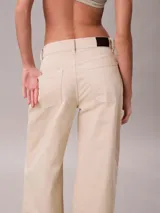 Pantalón chino de Calvin Klein, color beige, con diseño de pierna súper ancha, tiro alto, cinco bolsillos y cierre frontal con botón y cremallera.