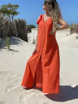 Vestido largo fucsia de lino, con corte recto, breteles anchos con volados y botones frontales. Presenta un tajo lateral.