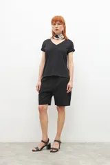 Remera negra de corte recto, con cuello en V y detalle de trenzas en los hombros.