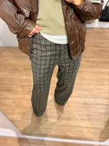 Pantalón sastrero de corte recto y tiro medio-alto, con estampado de cuadros en tonos grises y marrones. Presenta una cintura elástica que aporta comodidad y una textura de tela abrigada.