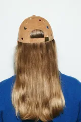 Gorra de béisbol confeccionada en pana color tostado, con diseño bordado de pájaros, lunas, corazones y estrellas en colores contrastantes. Cuenta con visera curva y ajuste posterior.